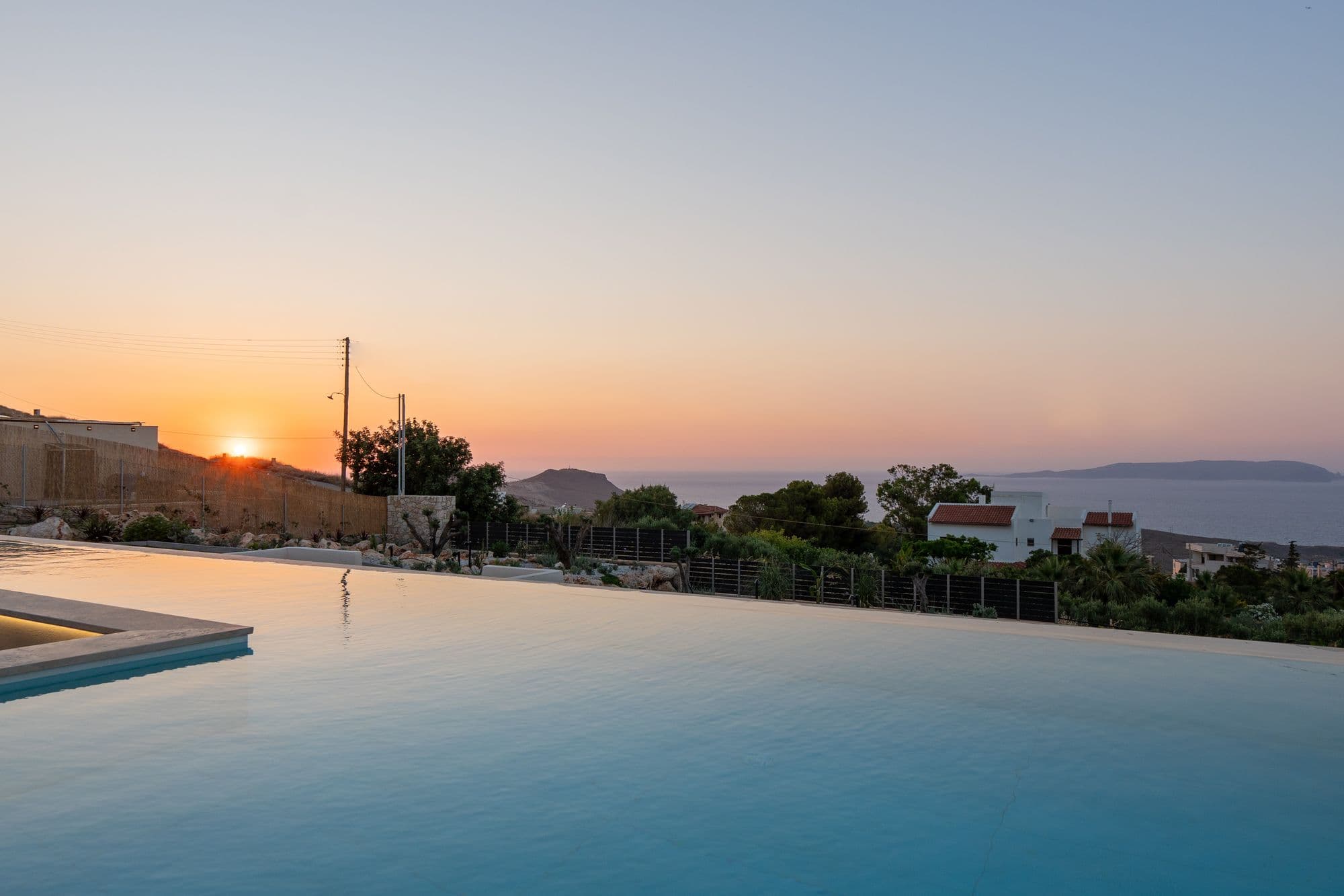 Stunning sunset over EOS Luxury Villa pool with Mediterranean Sea and distant islands