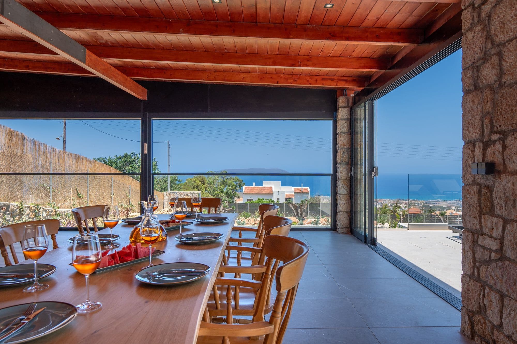 Covered terrace dining space with Mediterranean stone architecture and expansive sea horizon