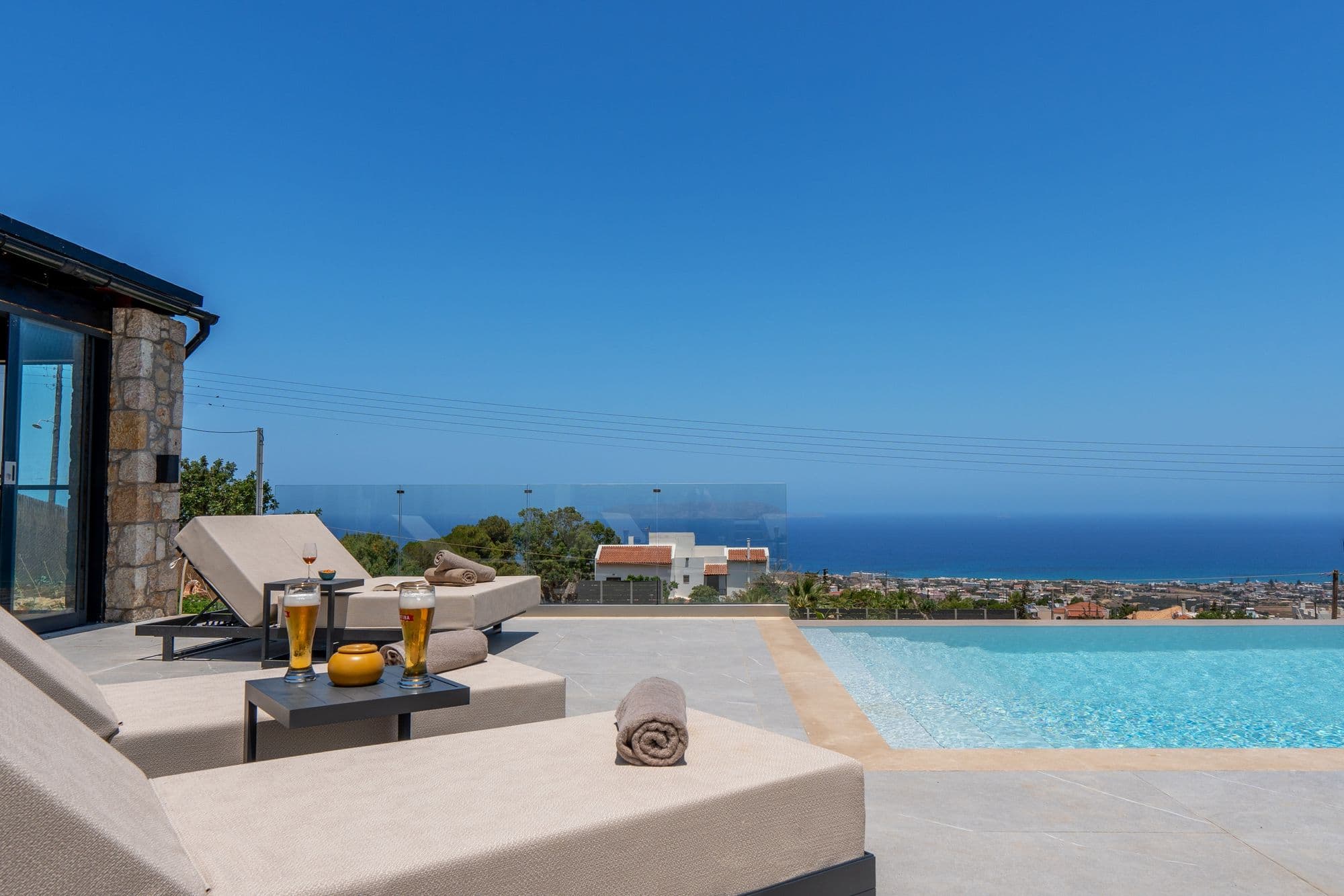 Elevated terrace with loungers, drinks by the pool edge and open sea views at EOS Luxury Villa